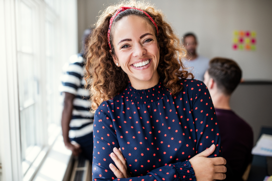 Close up of a woman smiling with people chatting behind her